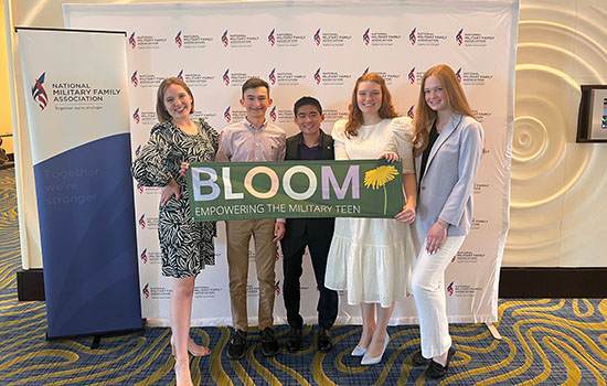 Bloom teens holding logo banner