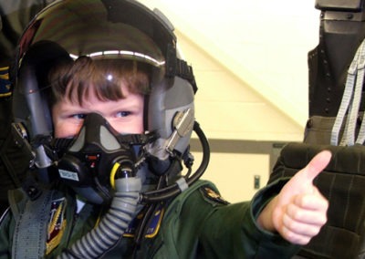 child wearing a flight mask gives thumbs up