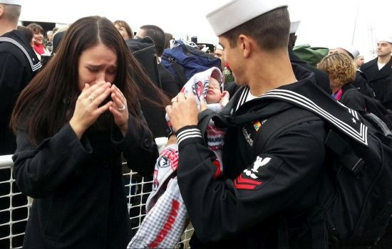 A Sailor holds his newborn for the first time. wife cries as navy husband holds baby
