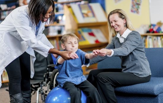 little boy with a disability doing therapy on yoga ball